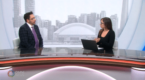 Paulo Rocha, especialista em finanças do Ganhos e Gastos, em entrevista à Kat Conniott no Focus Portuguese da OMNI News, discutindo a taxa de juros e a economia do Canadá com o horizonte de Toronto ao fundo.